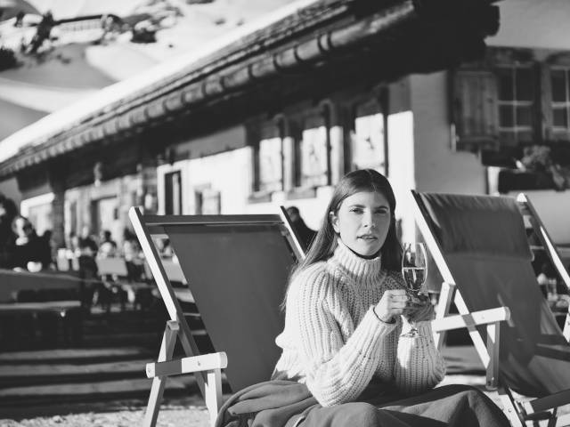 Woman sitting in a sun lounger and drinking a glass of champagne